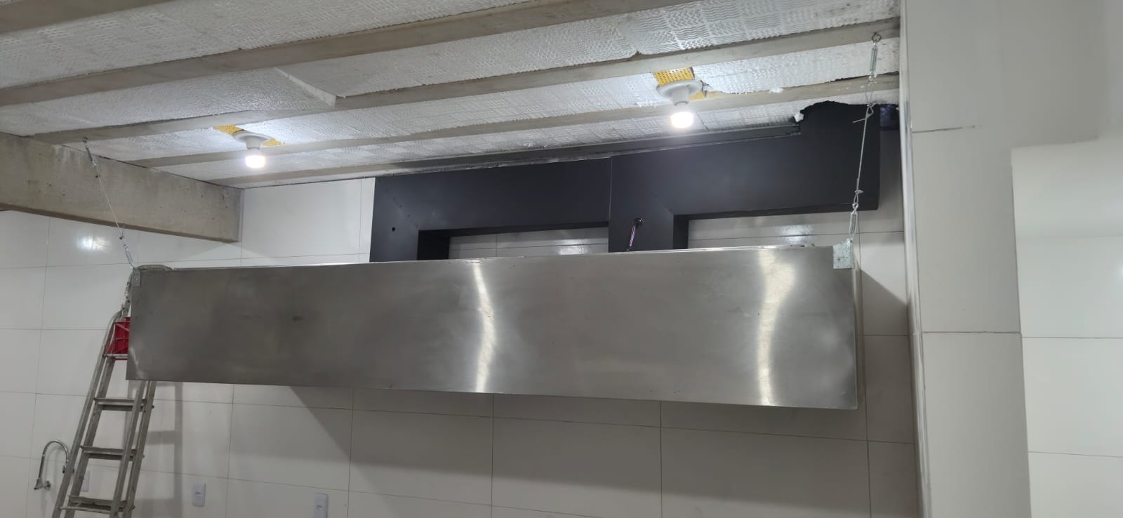 Vista frontal da coifa em aço inox e do duto em chapa galvanizada instalados em restaurante no Centro de Angra dos Reis